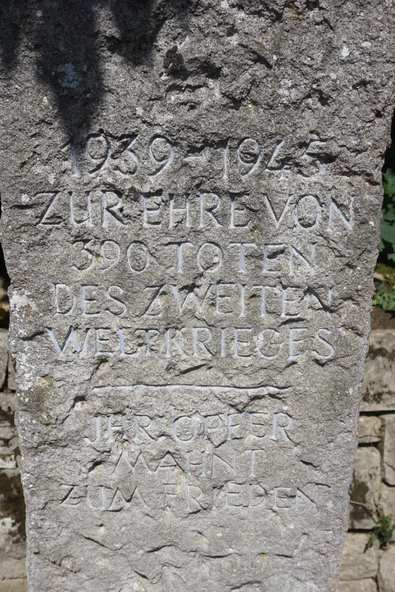 Napis na kamiennym krzyżu: 1939–1945 i. upamiętnienie 390 zmarłych II wojny światowej — KZ-Friedhof Kochendorf Cmentarz ofiar obozu w Bad Friedrichshall